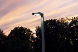 a protected LED outdoor streetlight against a setting sky.
